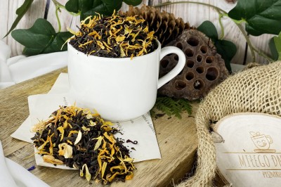 Ciemne liście czarnej herbaty z czerwonymi cząstkami hibiskusa złocistym słonecznikiem i pączkami jaśminu