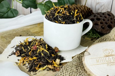 Ciemne liście herbaty pu-erh z kawałkami liofilizowanej truskawki i złocistymi płatkami słonecznika