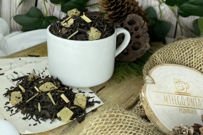 Ciemnobrązowe liście herbaty Pu-Erh z widocznymi żółtymi kostkami kandyzowanego ananasa i suszoną trawą cytrynową