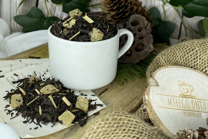 Ciemnobrązowe liście herbaty Pu-Erh z widocznymi żółtymi kostkami kandyzowanego ananasa i suszoną trawą cytrynową