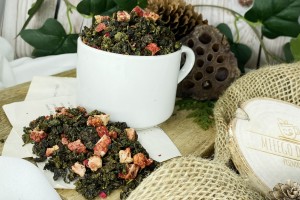 Ciemnozielone zwinięte liście herbaty oolong wymieszane z kawałkami czerwonych truskawek i purpurowymi płatkami kwiatu granatu