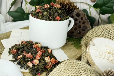 Ciemnozielone zwinięte liście herbaty oolong wymieszane z kawałkami czerwonych truskawek i purpurowymi płatkami kwiatu granatu