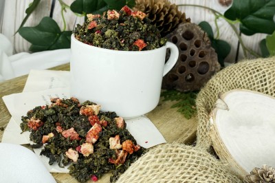 Ciemnozielone zwinięte liście herbaty oolong wymieszane z kawałkami czerwonych truskawek i purpurowymi płatkami kwiatu granatu