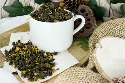 Ciemnozielone zwinięte liście herbaty oolong wymieszane z pomarańczową skórką żółtymi płatkami nagietka i kawałkami cynamonu