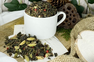 Niebieskozielone zwinięte liście herbaty oolong wymieszane z korą cynamonu imbirem kardamonem goździkami i ziarnami czerwonego pieprzu